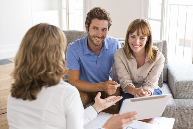 A couple meets with a Chartered Financial Analyst to review their investment portfolio from the comfort of their living room.