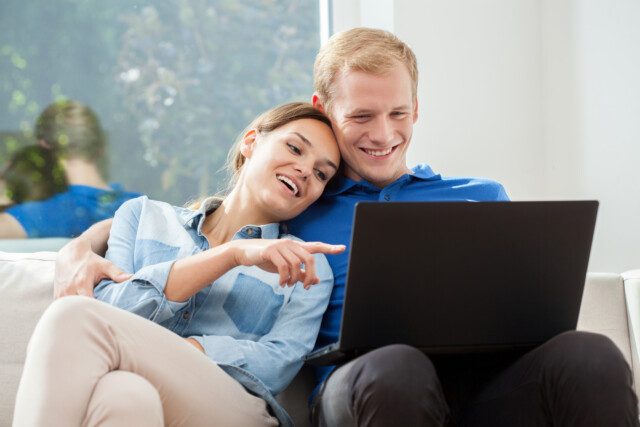 View of couple in love using internet to research financial advisors who can help them tackle their student loan debt.