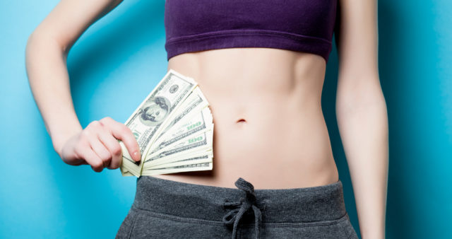 Woman holding money wearing workout clothes.